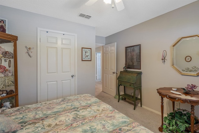 carpeted bedroom featuring ceiling fan and a textured ceiling