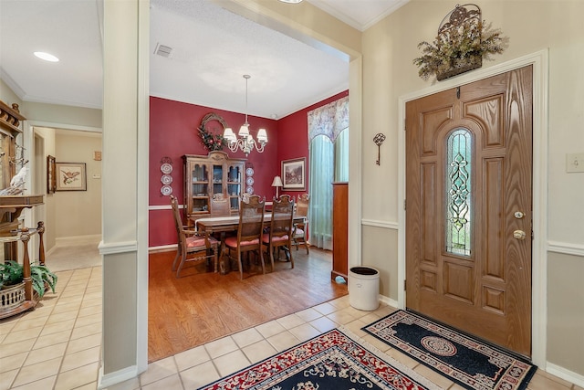 tiled foyer entrance with a chandelier and ornamental molding