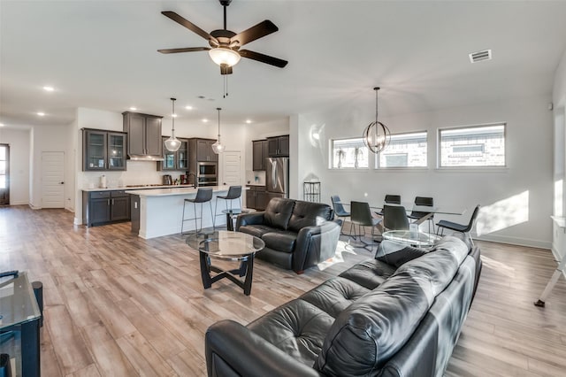 living room with light hardwood / wood-style floors and ceiling fan with notable chandelier