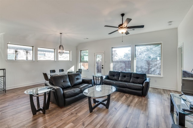 living room with ceiling fan with notable chandelier and light hardwood / wood-style flooring