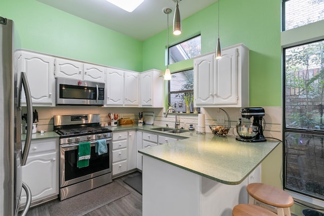 kitchen featuring sink, decorative light fixtures, white cabinetry, kitchen peninsula, and stainless steel appliances