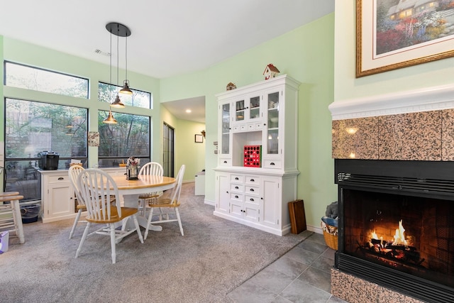 dining room with light colored carpet and a tile fireplace