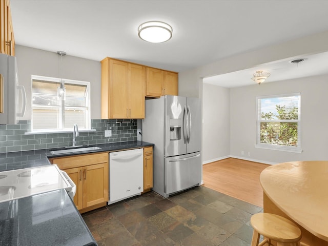 kitchen with pendant lighting, dishwasher, backsplash, sink, and stainless steel refrigerator with ice dispenser