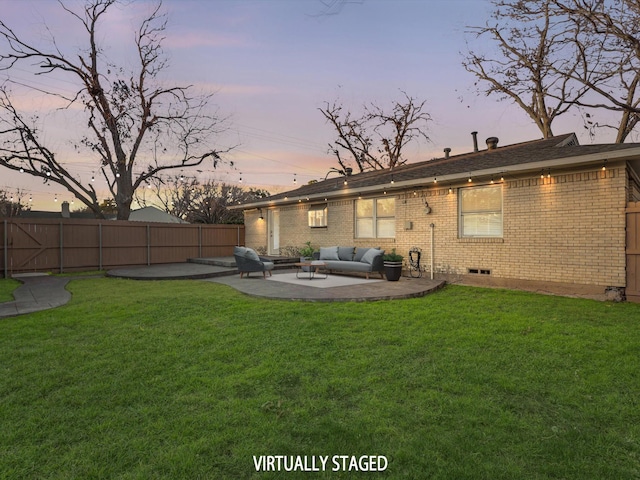 back house at dusk with a lawn, an outdoor hangout area, and a patio