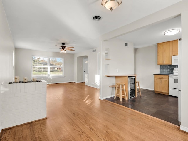 kitchen featuring dark hardwood / wood-style flooring, backsplash, white appliances, ceiling fan, and beverage cooler