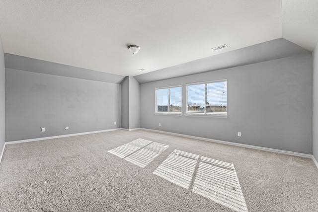 carpeted spare room with vaulted ceiling