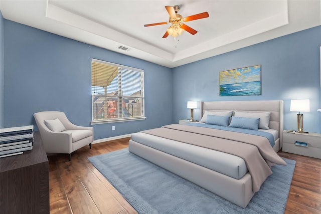 bedroom featuring dark hardwood / wood-style floors, a raised ceiling, and ceiling fan