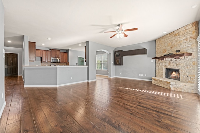 unfurnished living room with ceiling fan, dark hardwood / wood-style flooring, and a fireplace