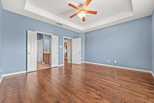 unfurnished bedroom featuring a tray ceiling, ceiling fan, and hardwood / wood-style flooring