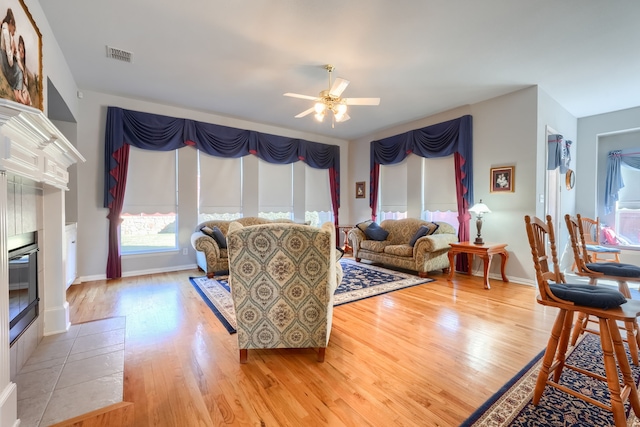 living room with ceiling fan, a fireplace, and light hardwood / wood-style floors