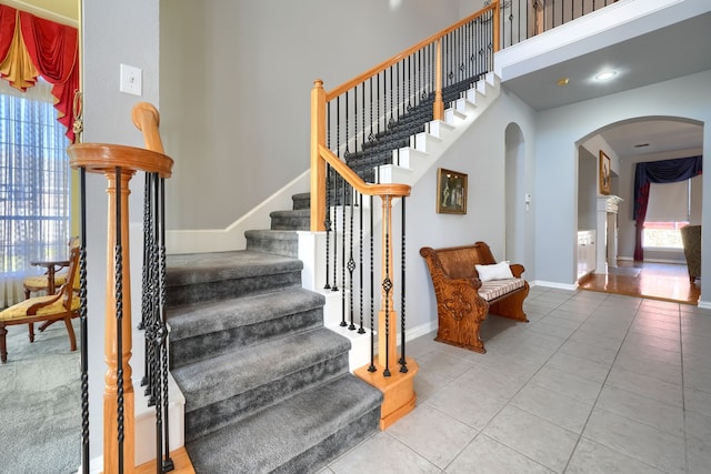 staircase with tile patterned flooring and a towering ceiling