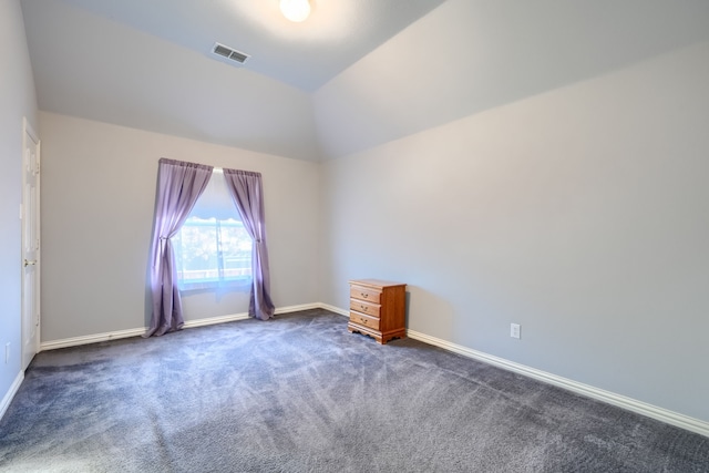 spare room with dark carpet and vaulted ceiling