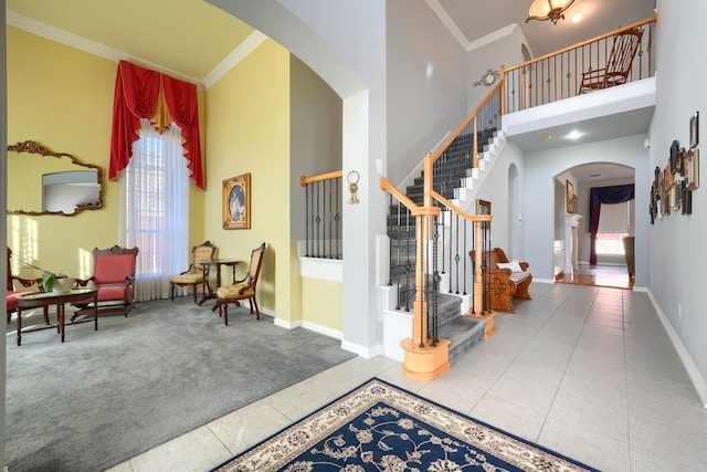 tiled foyer featuring ornamental molding and a high ceiling