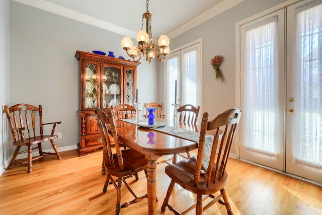 dining area featuring crown molding, french doors, light wood-type flooring, and an inviting chandelier