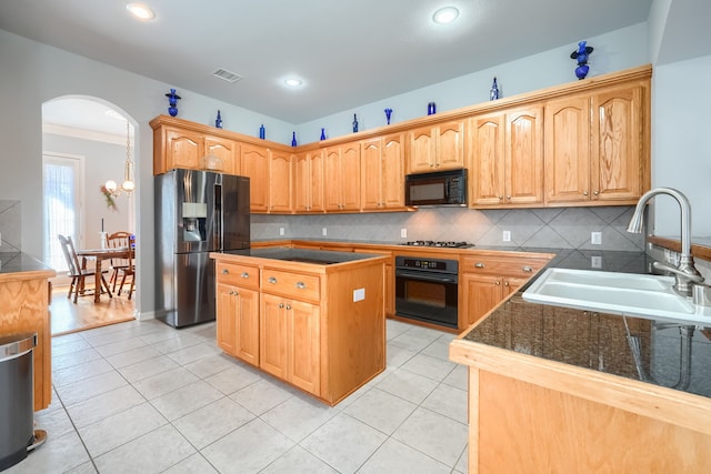 kitchen featuring ornamental molding, sink, black appliances, light tile patterned floors, and a center island