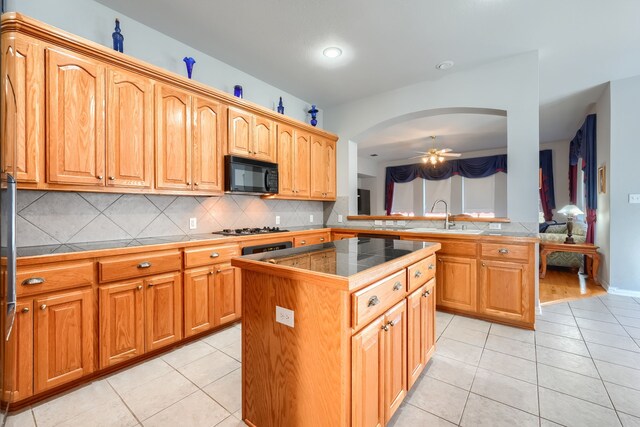 kitchen featuring kitchen peninsula, backsplash, ceiling fan, light tile patterned floors, and a kitchen island