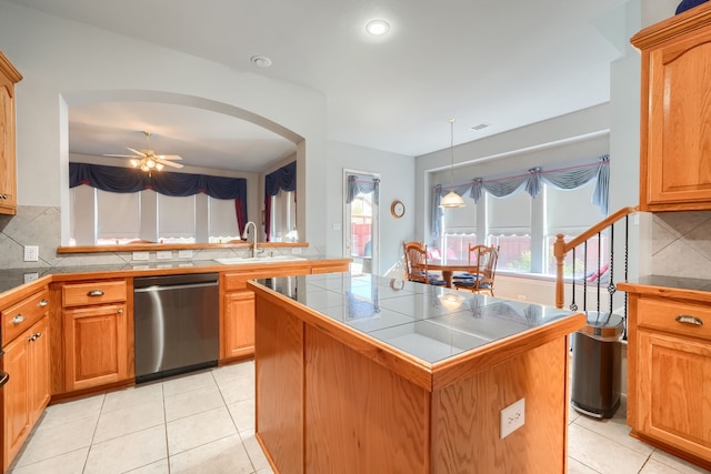 kitchen featuring tile countertops, dishwasher, sink, ceiling fan, and a kitchen island