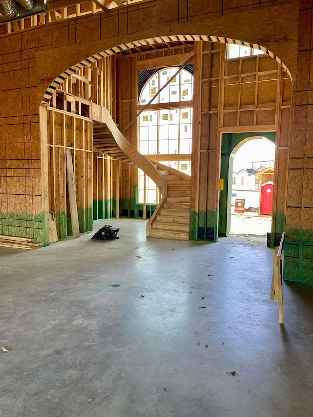 miscellaneous room featuring unfinished concrete flooring and a high ceiling