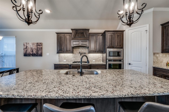 kitchen with appliances with stainless steel finishes, an inviting chandelier, a sink, and a kitchen breakfast bar