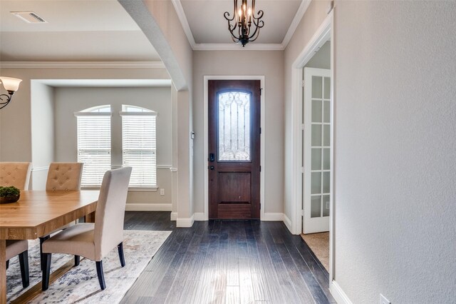 entryway featuring dark hardwood / wood-style floors, a healthy amount of sunlight, crown molding, and an inviting chandelier