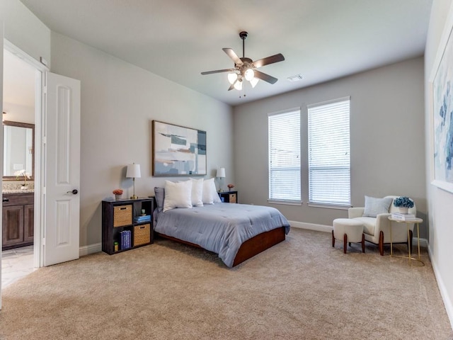 bedroom with ensuite bath, baseboards, visible vents, and light colored carpet