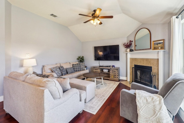 living room featuring ceiling fan, dark hardwood / wood-style flooring, lofted ceiling, and a tile fireplace