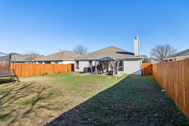 rear view of house with a gazebo, a yard, a patio, and a trampoline