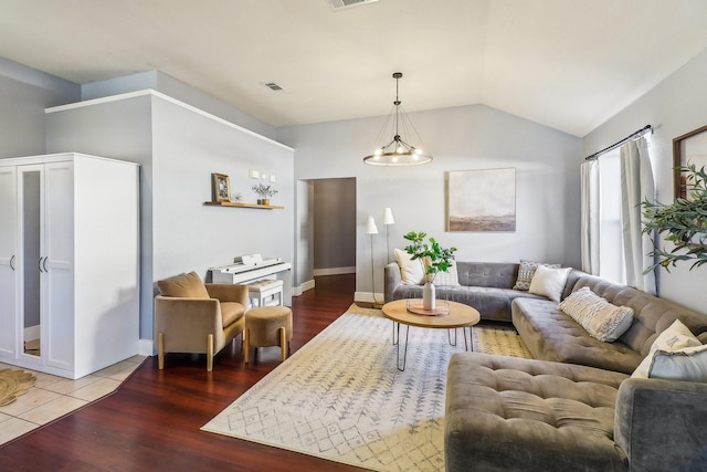 living room featuring hardwood / wood-style flooring, vaulted ceiling, and a notable chandelier