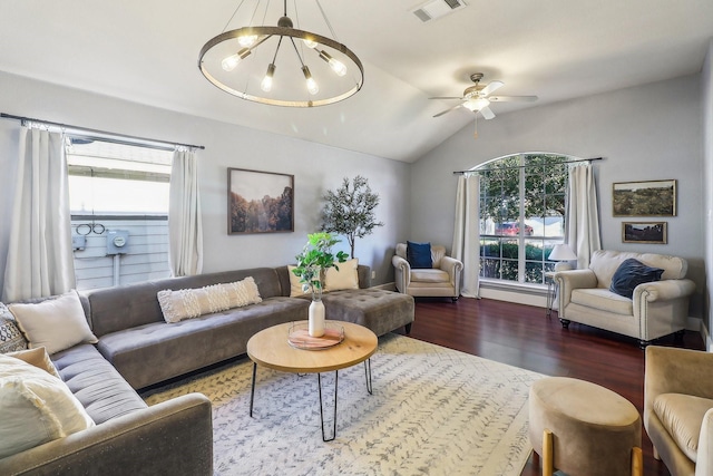 living room with ceiling fan with notable chandelier, vaulted ceiling, and dark wood-type flooring