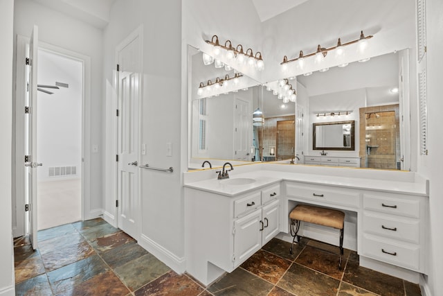 bathroom with visible vents, a tile shower, vanity, and stone tile floors