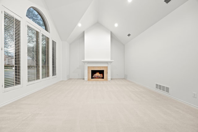 unfurnished living room featuring a fireplace with flush hearth, visible vents, high vaulted ceiling, and light carpet