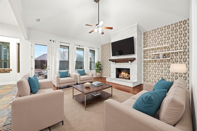 living room with lofted ceiling, ceiling fan, light wood finished floors, and a fireplace