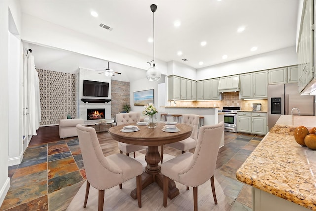 dining area featuring recessed lighting, stone tile flooring, visible vents, and a fireplace