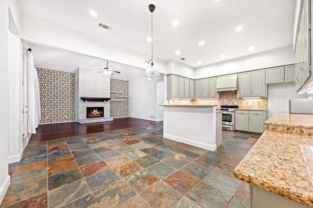 kitchen with stone tile floors, visible vents, open floor plan, stainless steel range oven, and a fireplace