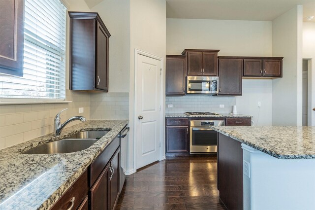 kitchen with light stone countertops, sink, dark hardwood / wood-style flooring, decorative backsplash, and appliances with stainless steel finishes