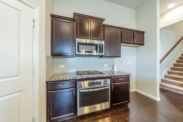 kitchen with light stone countertops, dark wood-type flooring, decorative backsplash, dark brown cabinets, and appliances with stainless steel finishes