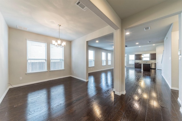 empty room with dark hardwood / wood-style flooring and a notable chandelier