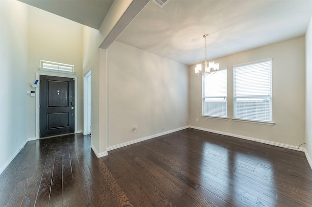 empty room featuring dark hardwood / wood-style flooring and a notable chandelier