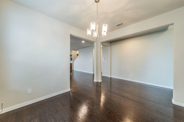 empty room featuring a notable chandelier and dark hardwood / wood-style flooring