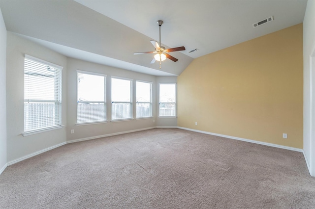 carpeted empty room featuring a wealth of natural light, ceiling fan, and vaulted ceiling