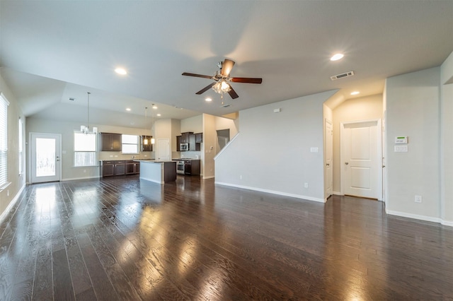 unfurnished living room with ceiling fan with notable chandelier, dark wood-type flooring, and lofted ceiling