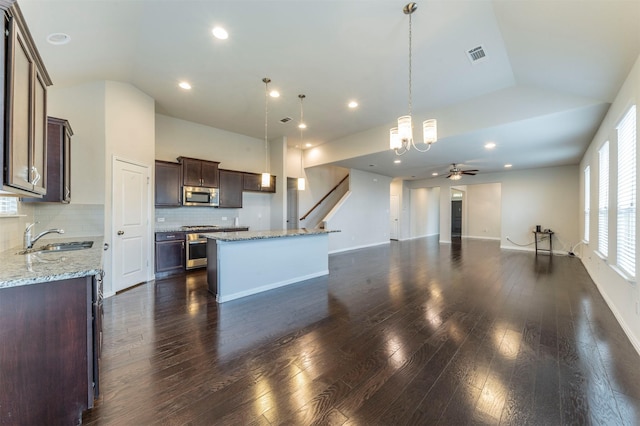 kitchen with backsplash, stainless steel appliances, sink, a kitchen island, and hanging light fixtures