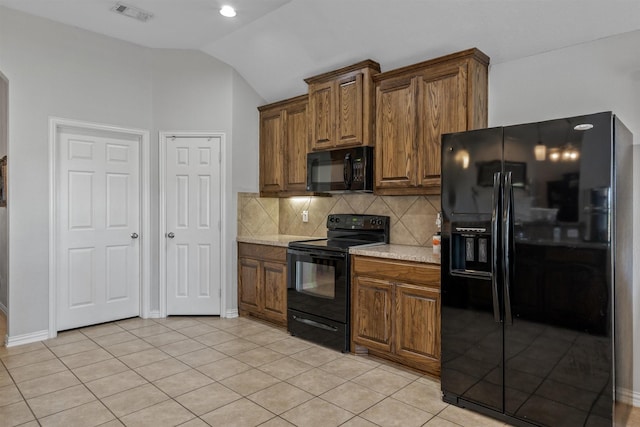 kitchen featuring lofted ceiling, light tile patterned floors, light stone countertops, black appliances, and decorative backsplash