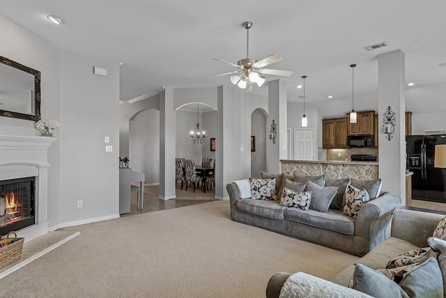 carpeted living room with ceiling fan with notable chandelier