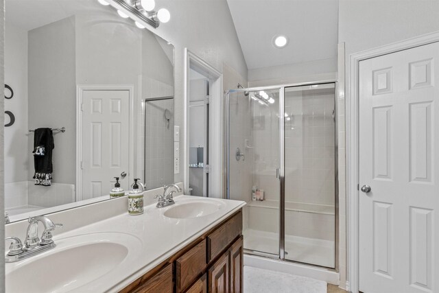 bathroom featuring vaulted ceiling, vanity, and a shower with door