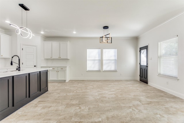 kitchen featuring crown molding, sink, pendant lighting, a chandelier, and white cabinetry