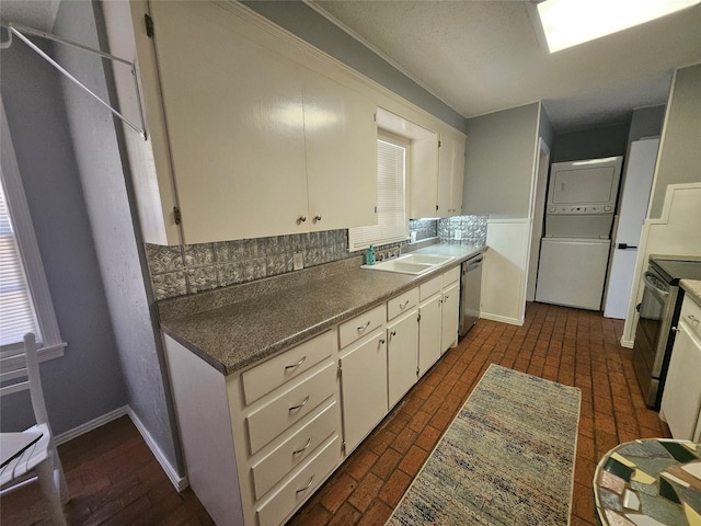 kitchen featuring stainless steel appliances, stacked washing maching and dryer, and white cabinets