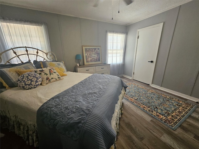 bedroom with ceiling fan, wood-type flooring, and a textured ceiling