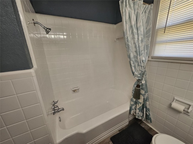 bathroom with tile walls, toilet, and shower / bath combo