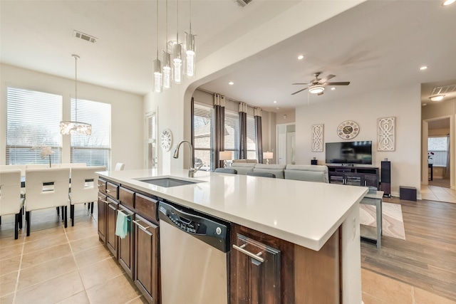 kitchen with sink, hanging light fixtures, stainless steel dishwasher, a center island with sink, and ceiling fan with notable chandelier